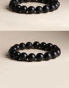 Detailed view of men's matte black beaded bracelet with natural wood texture beads