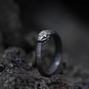 Macro detail of silver Ouroboros ring with realistic scale texture on volcanic rock