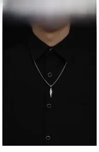 Gros plan d'un collier avec pendentif prisme géométrique pour homme sur une chemise noire