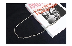 Close-up of polished silver rhombic titanium steel chain links on a white book surface