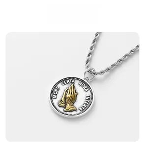 Macro detail of bicolored coin pendant featuring golden praying hands and Latin text