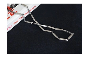 Detailed close-up of a silver polished titanium steel necklace with cylindrical links