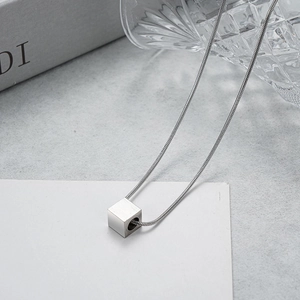 Detailed close-up of a silver minimalist cube pendant on a sleek snake chain necklace