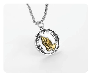 Macro view of religious medal pendant featuring golden praying hands and Latin text