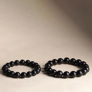 Men's vintage black wood bead bracelets with minimalist matte finish set on beige background