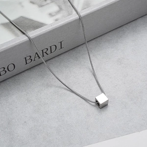 Macro shot of silver cube pendant on sleek snake chain with polished metal finish
