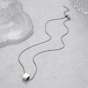 Macro shot of minimalist cube pendant necklace with sleek snake chain and adjustable clasp