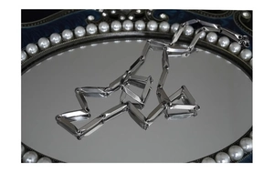 Polished silver geometric rectangle link chain displayed on a vintage pearl mirror