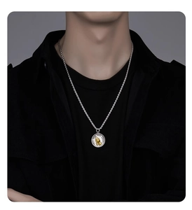 Detail of vintage silver chain necklace with a gold-tone praying hands coin pendant