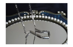 Detailed view of a silver geometric chain necklace reflecting on a vintage vanity mirror