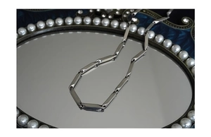 Macro shot of silver bamboo chain necklace on a vintage mirror tray with pearls