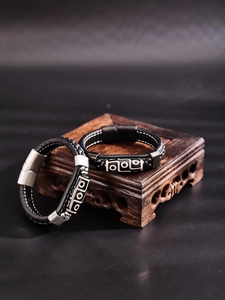 Détail de bracelets tibétains en cuir avec breloques géométriques sur socle en bois