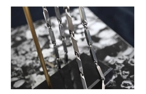 Macro shot of dark grey diamond-cut geometric titanium steel chain links on a stand