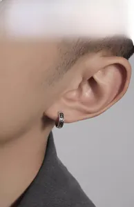 Close-up of vintage S925 silver hoop earring with Celtic patterns on male model ear