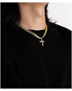 Macro detail of male two-tone angel wing cross pendant on a sleek snake chain