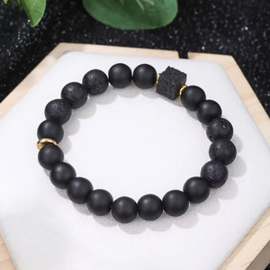 Detail of matte black beads and porous volcanic stone bracelet with gold accents
