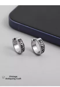 Macro shot of vintage silver earrings featuring intricate engraved scrollwork patterns