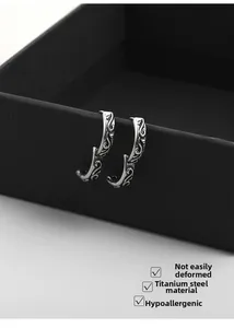 Detail of vintage silver hoop earrings in titanium steel with intricate floral engraving