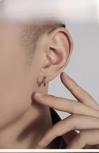 Macro detail of men's silver hoop earring with vintage engraved patterns on model