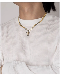Detail of two-tone gold and silver cross pendant with wings on a flat snake bone chain