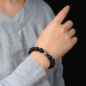 Men's volcanic stone bracelet with silver filigree bead on model's wrist