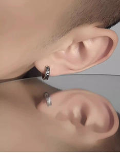 Macro shot of retro silver hoop earring with engraved totem patterns on a male model