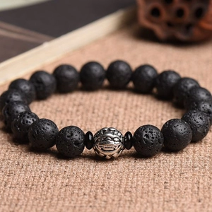 Men's volcanic lava stone bracelet with vintage silver beast bead on brown fiber background