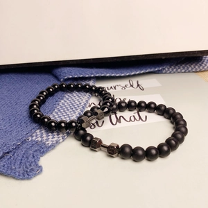 Detail von Fitness-Armbändern mit schwarzen Vulkanstein-Perlen und Metall-Hantel-Anhänger