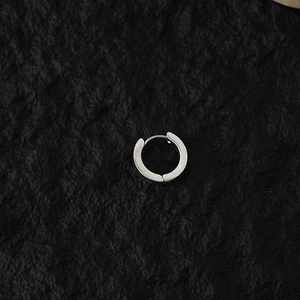 Close-up of a silver punk-style clip-on hoop earring with a minimalist industrial design