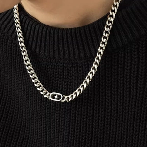 Dettaglio catena cubana argento con pendente a stella nera indossata su maglione nero