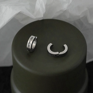 Close-up of matte silver rune earrings with Nordic engravings and vintage punk style finish