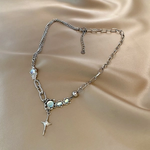 Detail of silver asymmetric star cross necklace with glowing moonstone on silk