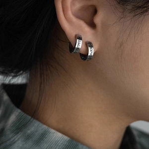 Macro side view of vintage punk ear cuffs with engraved runes in a matte silver finish