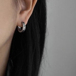 Detail of silver huggie earring with engraved Nordic runes and vintage punk style finish