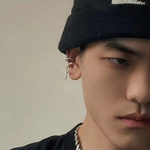 Silver cross clip-on earring with textured vintage finish on male model with black beanie
