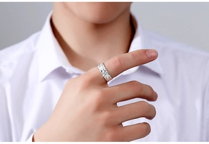 Detail eines Silberrings mit diagonaler Textur, getragen am Finger zu weißem Hemd