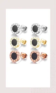 Close-up of titanium earrings with Roman numerals in silver, gold, and rose gold finish