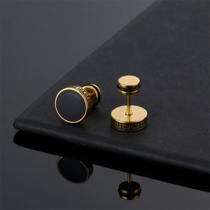 Macro detail of gold barbell studs with black inlay and Greek meander pattern engravings