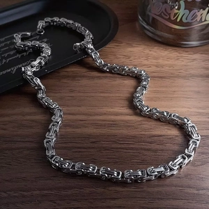 Mens Byzantine chain necklace in silver stainless steel on dark wood grain background