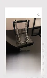 Gros plan d'un collier chaîne argentée punk industriel sur un support miroir noir