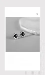 Detailed close-up of a silver stud earring with deep blue stone and twisted metal edge