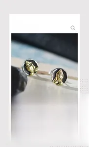 Macro detail of vintage round stud earrings with golden praying hands relief design