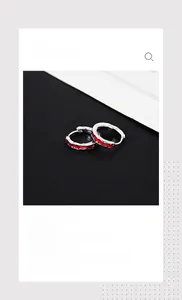 Close-up of silver hoop earrings with red wavy enamel texture on black background