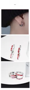 Close-up of silver earrings with red wavy enamel pattern and secure hoop closure