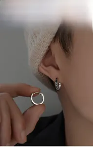 Detail of silver S925 earring showing black star relief pattern on the circular band