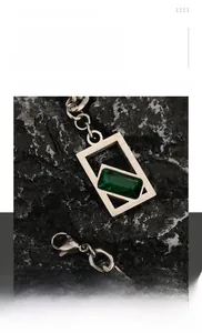 Détail d'un collier hip-hop en acier titane avec pierre précieuse vert émeraude sur roche
