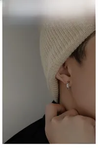 Macro detail of silver chain texture hoop earring on model with minimalist streetwear style