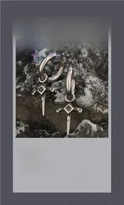 Detail of silver hoop earrings with black zircon cross sword pendant on dark stone