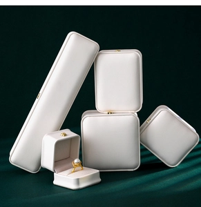Estuches de joyería en cuero blanco con cierres dorados sobre terciopelo para anillos y collares