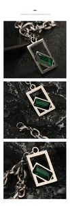 Détail macro du collier géométrique avec pendentif argenté et pierre précieuse émeraude